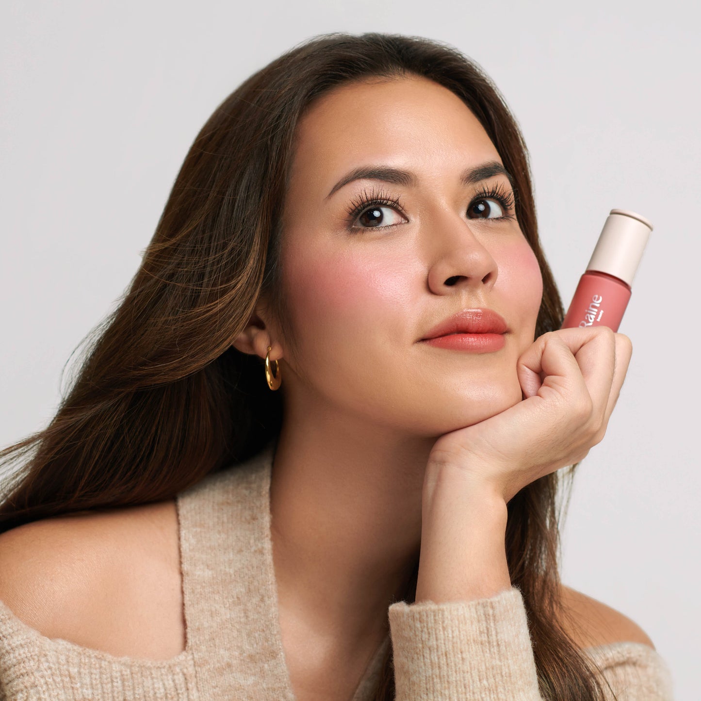 Woman holding a lipstick against a plain background